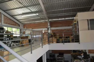 Espaço interno com teto de metal e paredes de tijolo visíveis.