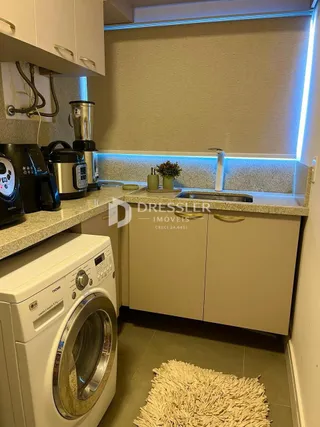 Vista interna de uma cozinha com armários brancos e eletrodomésticos.