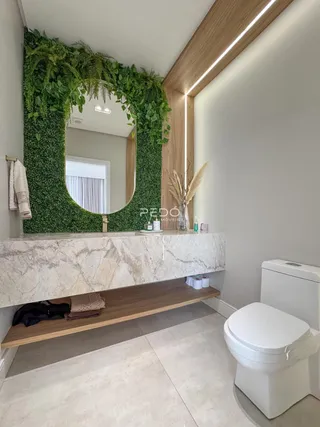 Banheiro com bancada de mármore e decoração verde.