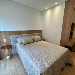 Quarto com cama de casal e cabeceira em um ambiente claro.