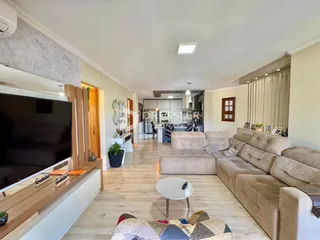 Sala de estar ampla com piso de madeira clara.