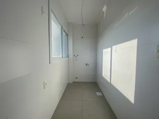 Corredor interno com paredes brancas e piso claro, mostrando a iluminação natural de uma janela.
