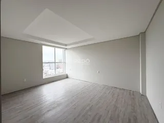Sala de estar com piso de madeira clara e grande janela.