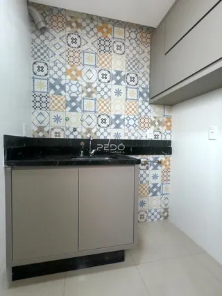 Detalhe de um banheiro com revestimento de azulejos decorativos e bancada de granito.