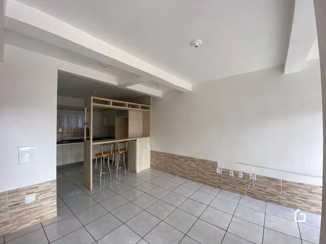 Hall de entrada com piso de cerâmica e armários de madeira visíveis.