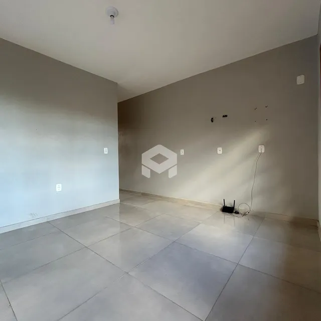 Interior de uma sala com piso de cerâmica clara e paredes brancas.