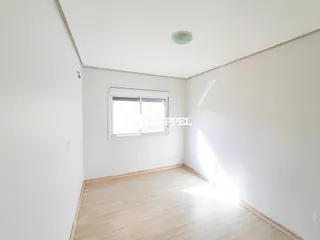 Foto de um cômodo interno com paredes brancas e piso de madeira clara.