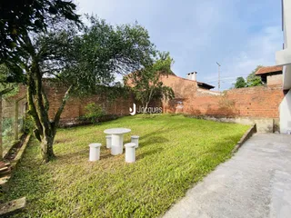 Vista externa de um jardim com gramado e muro de tijolos.