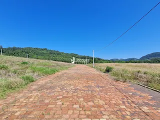 Uma estrada de tijolos se estende por uma paisagem de campo com colinas ao fundo.