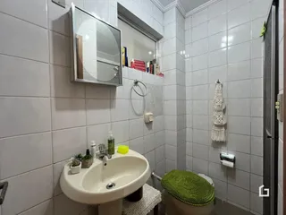 Banheiro com revestimento de cerâmica branca nas paredes.