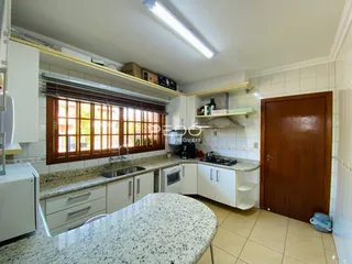 Cozinha com armários brancos e bancadas de granito em um imóvel no Brasil.