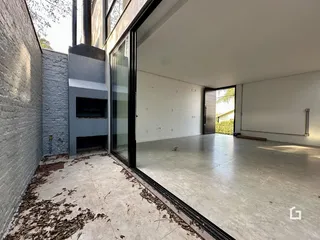 Vista de um ambiente interno com piso de concreto e porta de vidro.