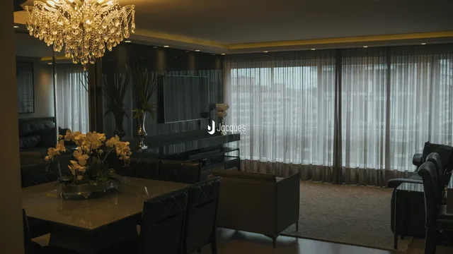 Sala de estar com decoração escura e cortinas claras.