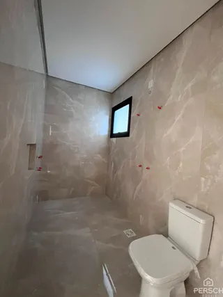Foto interna de um banheiro com paredes claras e um vaso sanitário branco.