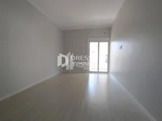 Corredor interno de uma residência com piso de madeira clara e paredes brancas.