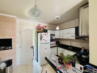 Foto da cozinha de uma residência com armários brancos e bancadas escuras.