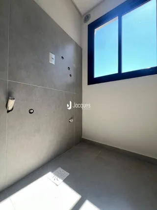 Vista de um canto de um ambiente interno com parede cinza e janela.