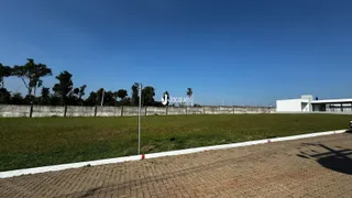 Vista externa de um terreno gramado com muro e cerca.