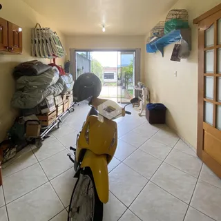 Interior de uma sala com piso de cerâmica e um veículo estacionado.