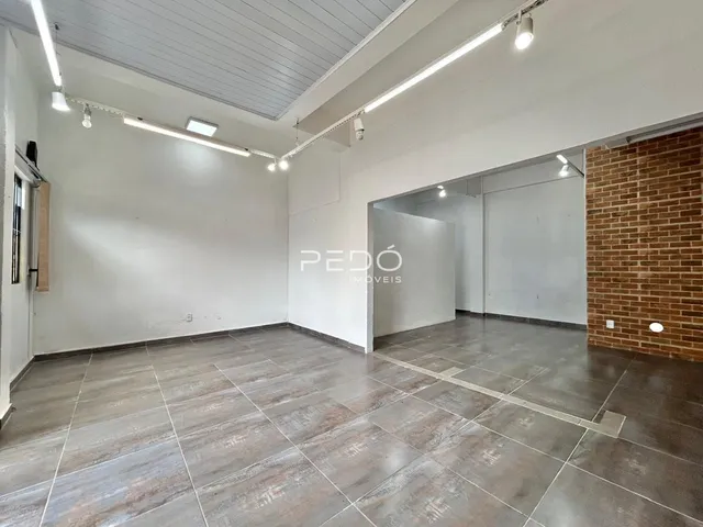 Imagem de um espaço interno amplo com piso de cerâmica e teto branco.