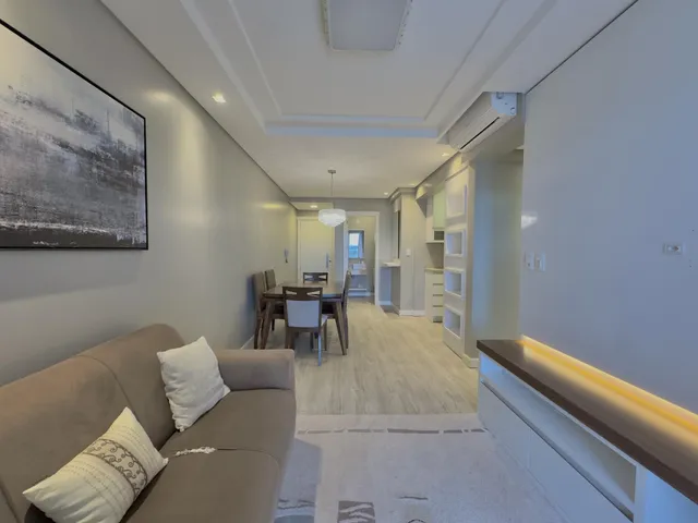 Sala de estar com sofá e mesa de jantar em um apartamento moderno.