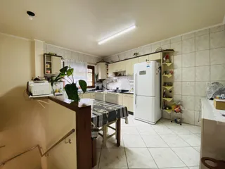 Foto da cozinha de uma residência com armários brancos e piso de cerâmica.