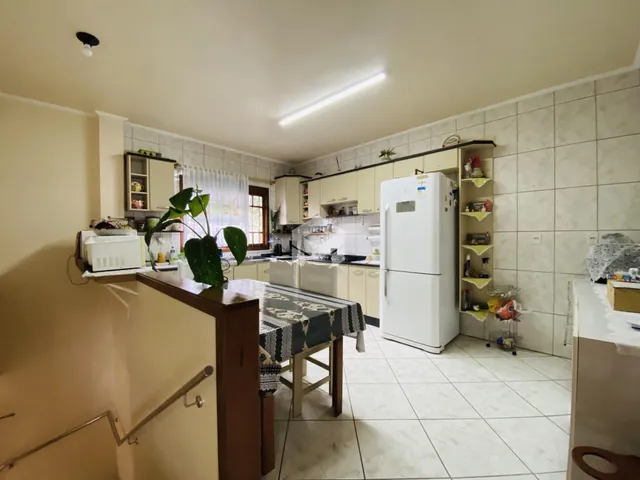 Foto da cozinha de uma residência com armários brancos e piso de cerâmica.