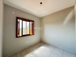 Vista interna de um cômodo com janela de madeira e piso de cerâmica.