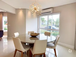 Uma sala de jantar com mesa redonda e grandes janelas.