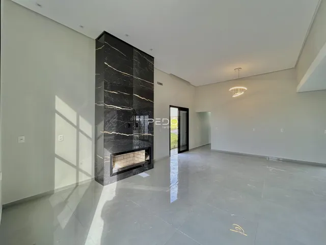 Sala de estar ampla com parede de mármore escura e piso claro.