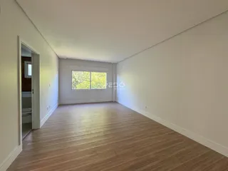 Sala de estar com piso de madeira clara e paredes brancas.