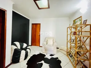 Sala de estar com sofá e poltrona brancas em um ambiente claro.