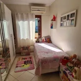 Uma foto interna de um quarto com cama e cortinas claras.