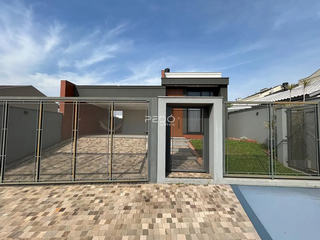 Vista da fachada de uma residência moderna com área externa cercada.
