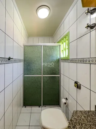 Corredor de banheiro com revestimento cerâmico branco.