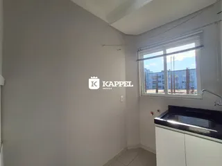 Foto interna de uma cozinha com janela que mostra uma construção externa.