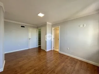 Hall de entrada com piso de madeira e portas brancas.