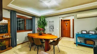 Uma sala de jantar com mesa de madeira e cadeiras é visível no interior da propriedade.