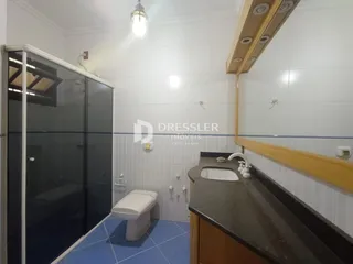 Foto de um banheiro com revestimento cerâmico e box de vidro.