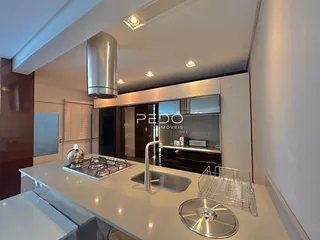 Cozinha moderna com bancada branca e eletrodomésticos de aço inoxidável.