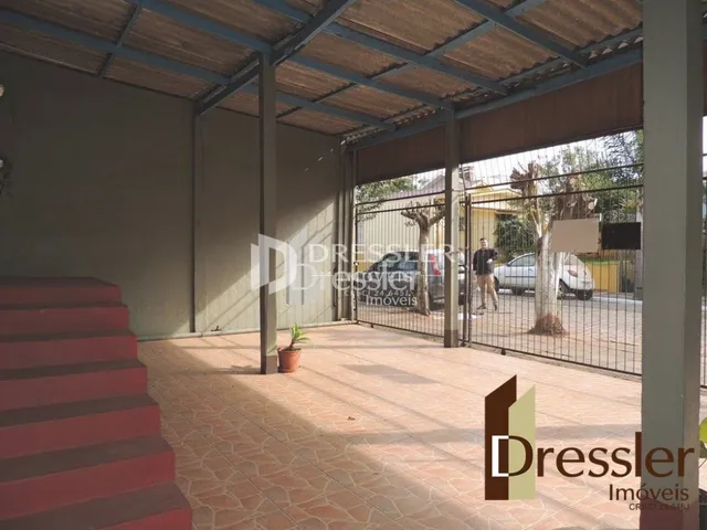 Vista de uma área externa com piso de cerâmica e cerca de tela.