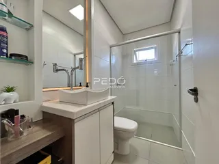 Banheiro moderno com box de vidro e bancada de mármore.
