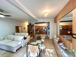Sala de estar com sofá branco e mesa de centro de vidro em um imóvel em Lajeado.