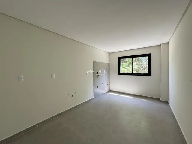 Ambiente interno de uma sala ampla com paredes brancas e piso de concreto.