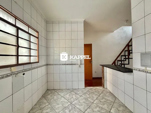 Foto interna de um ambiente com revestimento de azulejos brancos e piso de porcelanato.