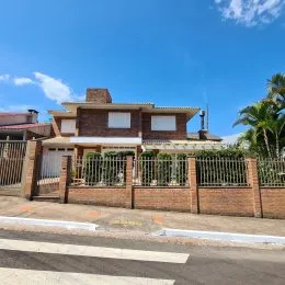 Fachada de uma casa residencial em Lajeado, Brasil, com muro de tijolos e vegetação.