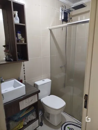 Foto de um banheiro com pia e box de vidro.