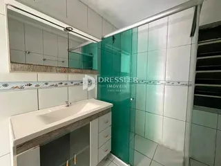 Banheiro com revestimento cerâmico e bancada branca.