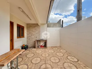 Vista de uma área externa com piso de cerâmica e parede branca.