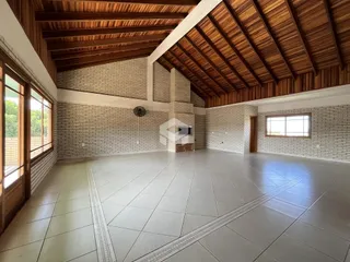 Interior de uma sala ampla com teto de madeira e paredes de tijolo.